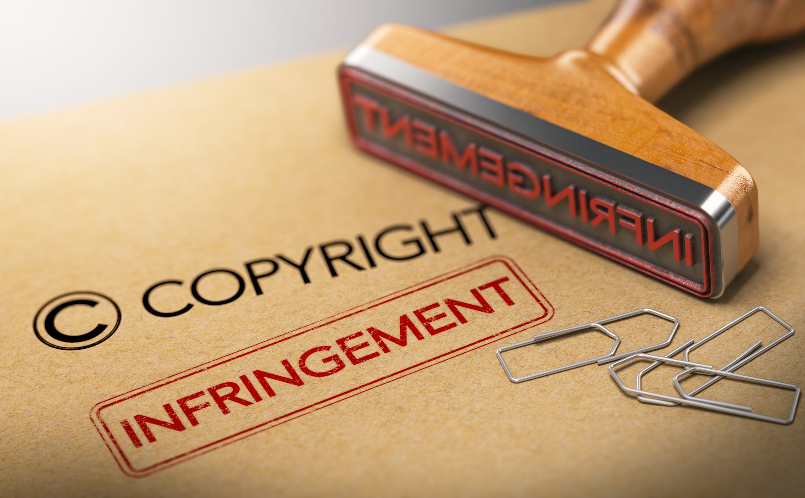 3D illustration of rubber stamp with the words copyright and infringement over kraft paper background, Concept of intellectual property.
